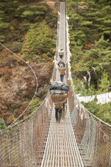Porters crossing a suspension bridge over the Dudh Kosi, Everest Base Camp trek, Khumbu, Nepal - obrazy, fototapety, plakaty