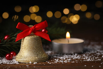 Bell with red bow and Christmas decor on wooden table against blurred background. Space for text