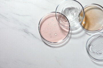Petri dishes with liquids on white marble table, flat lay. Space for text