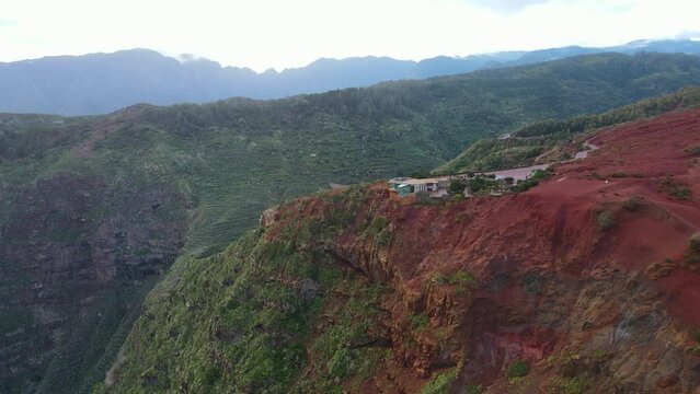Aerial view of stunning viewpoint Mirador de Abrante with glass observation balcony above Agulo village in La Gomera island at sunrise. Restaurant on red clay.