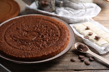 Delicious homemade sponge cake and different kinds of chocolate on wooden table, closeup