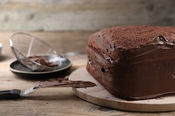 Delicious homemade layer cake with chocolate cream on wooden table, closeup
