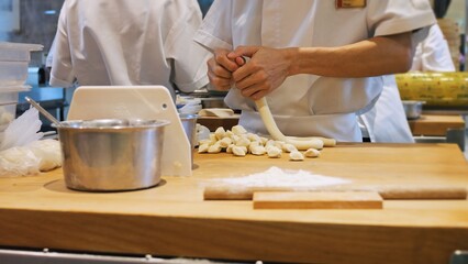Restaurants great chefs at work on exquisite gourmet dishes. Cooking dough for dumplings in a Chinese restaurant, the chef divides the dough into small pieces for wrapping minced meat in them