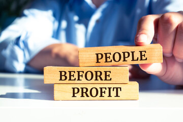 Closeup on businessman holding a wooden blocks with text PEOPLE BEFORE PROFIT, business concept