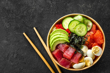 Poke bowl with tuna, avocado, grapefruit, eggs and cucumbers in paper lunch box for take away or...