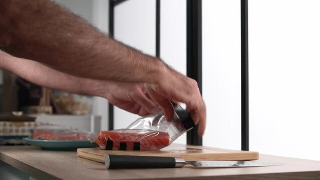 detail of a man's hands holding a loin of salmon in a freezer bag