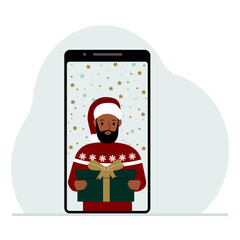 Video congratulations Merry Christmas or New Year. Mobile phone with a man in a red cap with a gift box. The concept of a safe celebration, online congratulations.