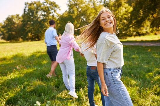Lachendes M&auml;dchen l&auml;uft mit Familie &uuml;ber Wiese