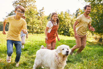 Familie und zwei Kinder laufen mit ihrem Hund