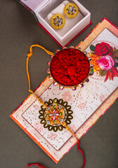 Indian traditional Festival Rakhi with rice grains, kumkum and gift envelope on background with an elegant Rakhi. A traditional Indian wrist band which is a symbol of love between Brothers and Sisters