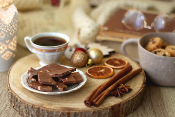 Cup of tea or coffee, various sweets and spices, Christmas decorations, comfy blanket, books and glasses. Selective focus.