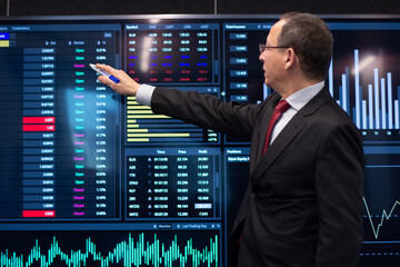 Financial expert working with stock market data. Serious man in formalwear standing near digital display showing currency growth with marker and analyzing trends. Financial analytics, business concept