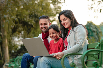 Fototapeta na wymiar Indian family using laptop at park