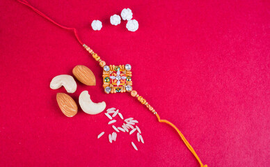 Indian traditional Festival Rakhi with rice grains, kumkum and gift envelope on background with an elegant Rakhi. A traditional Indian wrist band which is a symbol of love between Brothers and Sisters