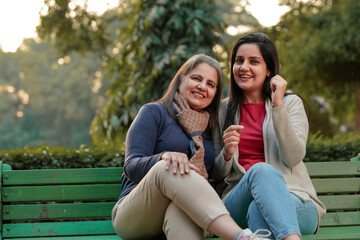 Fototapeta na wymiar Two indian woman sitting at park in winter wear