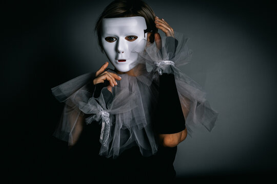 Woman in white theater mask and harlequin collar on black background. Fancy dress, masquerade c lothes. High quality photo