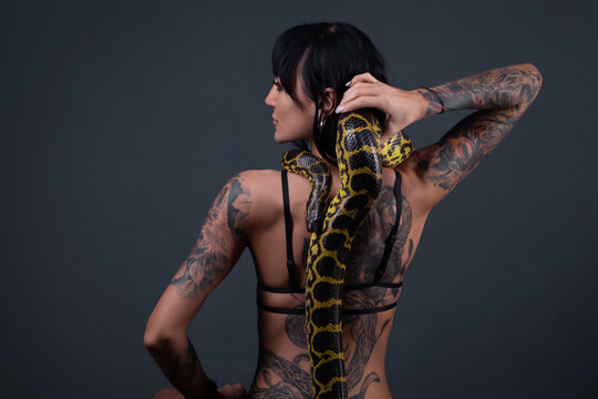 Image of the woman from back holding anaconda along the spine
