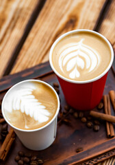 Two paper cups of cappuccino coffee on woden table background