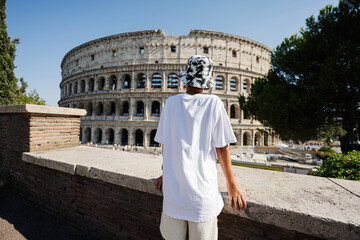 Back of boy tourist enjoy view Colosseum in the old city center of Rome, Italy.