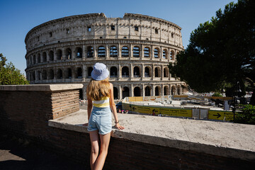 Fototapeta na wymiar Back of girl tourist enjoy view Colosseum in the old city center of Rome, Italy.