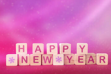 Wooden blocks with words Happy New Year over pink abstract Christmas background