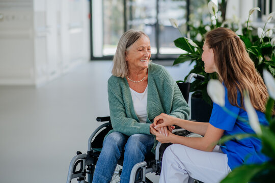 Young woman doctor taking care of senior woman at wheelchair.