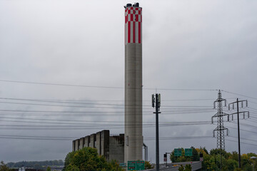 Obraz premium Chimney of power plant with power line cables and pylons at City of Zürich on a cloudy rainy autumn day. Photo taken October 1st, 2022, Zurich, Switzerland.