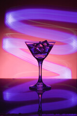 Martini glass with ice. On the bar. Against the background of neon light.