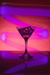Martini glass with ice. On the bar. Against the background of neon light.