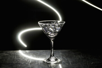 Martini glass with ice. On the bar. Against the background of neon light.