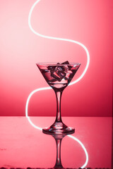 Martini glass with ice. On the bar. Against the background of neon light.