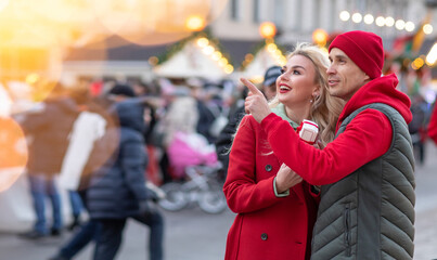 Happy caucasian couple in love on date walking city streets Christmas fair time over light bokeh. Pastime together. Romantic, love family and greeting concept New Year winter. Copy space