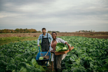 Shot of an attractive young female and male farmers in working clothes carrying a crate of fresh...