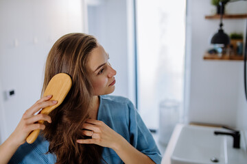 Young woman taking care of her hair, morning beauty routine concept.