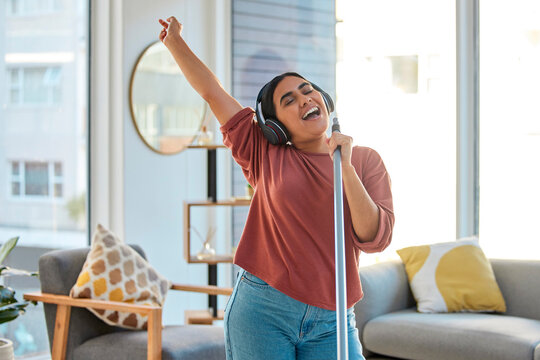 Music, Headphones And Woman Singing While Cleaning Home, Dancing And Having Fun. Singer, Dance And Female Spring Cleaning For Hygiene Holding Broom Like Microphone, Sweeping Dust And Streaming Radio.