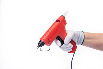 Red electric glue gun. On a white isolated background. The glue gun is held by a human hand in a...