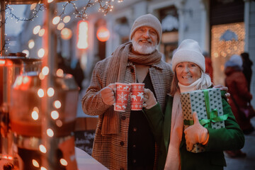 Happy senior couple enjoying christmas market, buying gifts.