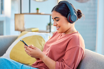 Indian woman, music headphones and smartphone in living room for social media app, radio podcast...