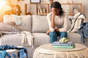 Black woman, stress and headache in depression on sofa from dirty living room or goblin mode at home. Stressed African American female tired, frustrated or suffering in mental health burnout on couch - obrazy, fototapety, plakaty