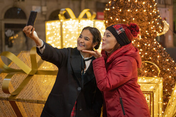 Group of attractive young women of different ethnicities taking a selfie in christmas time -...