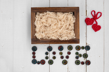 Newborn digital backdrop with wooden box, two handmade hearts and word love with buttons on white wooden background. Newborn white wooden background. Newborn background. Top view.