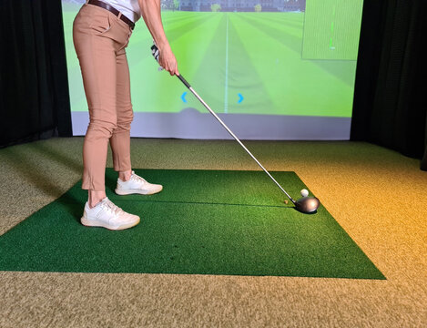 Professional Female Golfer Playing Golf Indoors On Golf Simulator Closeup