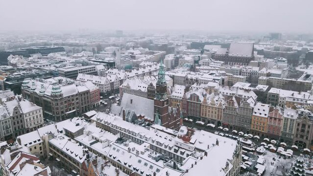 Winter aerial view with snowfall on old city of Wroclaw and market square with townhall 4k