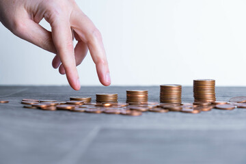 Fingers of a person climbing several piles of Euro coins. Inflation concept, trade price increase