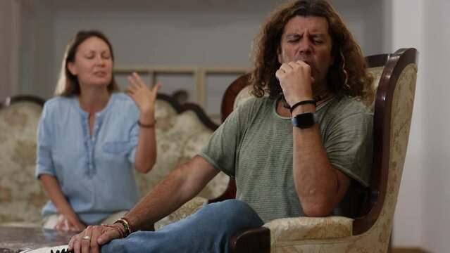 Portrait of upset man sitting while quarrel with wife at home interior