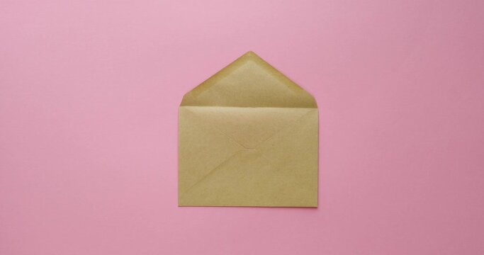 Mail craft envelope and paper hearts on a pink background. Romantic message. 4K stop motion animation