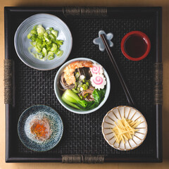 Japanese  Soba Noodle Soup with  shrimps tempura  with ingredients and toppings on an authentic tray.  Soba Noodles on New Year’s Eve made from buckwheat flour. Square crop