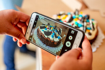 Homemmade chocolate cake decoration. Person taking photo of a chocolate cake made at home.