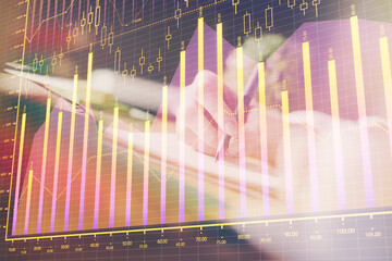 Financial forex graph displayed on hands taking notes background. Concept of research. Multi exposure