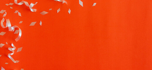 close up on group of silver color of rolling ribbon and confetti on orange background with copy space for happy new year ,carnival , birthday and anniversary, concept design